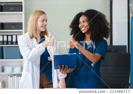 Successful team female doctor standing at table, looking at camera. Successful team female doctor standing at table, looking at camera. 121466717