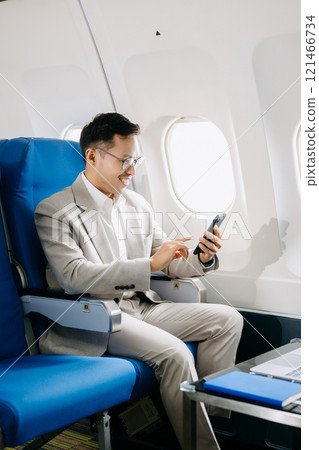 Young Asian executive excels in first class, multitasking with digital tablet, laptop and smartphone. Young Asian executive excels in first class, multitasking with digital tablet, laptop and smartphone. 121466734