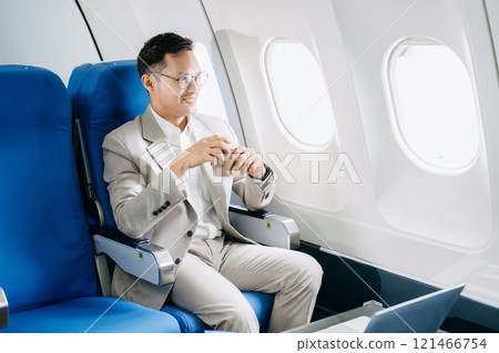 Young Asian executive excels in first class, multitasking with digital tablet, laptop and smartphone. Young Asian executive excels in first class, multitasking with digital tablet, laptop and smartphone. 121466754