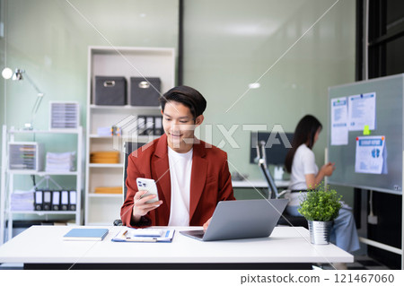 Confident Asian man with a smile standing holding notepad and tablet at the modern office. Confident Asian man with a smile standing holding notepad and tablet at the modern office. 121467060