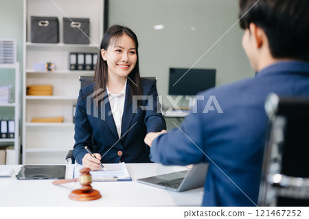 Two lawyers are discussing about contract paper, law matters determination, pointing.law and hammer on the table 121467252