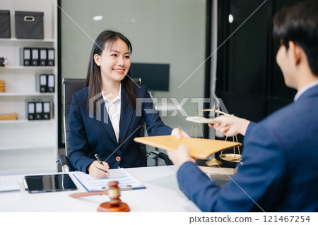 Two lawyers are discussing about contract paper, law matters determination, pointing.law and hammer on the table 121467254