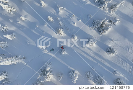 Aerial view of ski touring man and woman with snow shoes crossing winter mountains, fresh snow. Aerial view of ski touring man and woman with snow shoes crossing winter mountains, fresh snow. 121468776