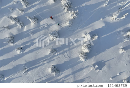 Aerial view of ski touring man and woman with snow shoes crossing winter mountains, fresh snow. Aerial view of ski touring man and woman with snow shoes crossing winter mountains, fresh snow. 121468789