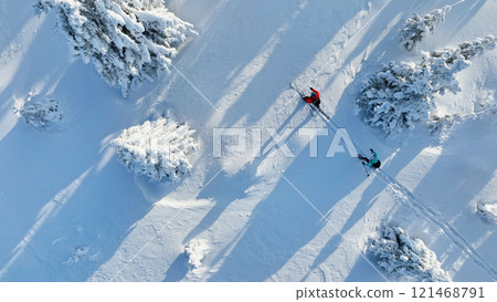 Aerial view of ski touring man and woman with snow shoes crossing winter mountains, fresh snow. 121468791