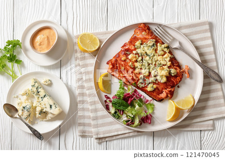 baked salmon topped with blue cheese on a plate 121470045