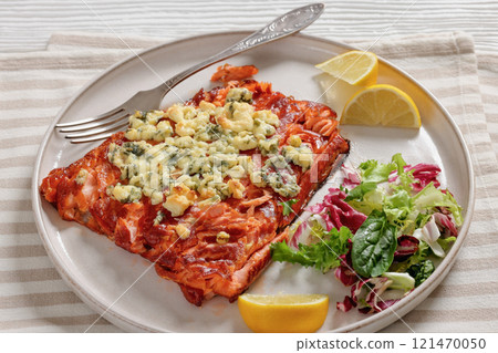 baked salmon topped with blue cheese on a plate 121470050