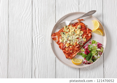baked salmon topped with blue cheese on a plate 121470052