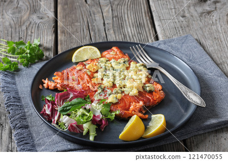 baked salmon topped with blue cheese on a plate 121470055