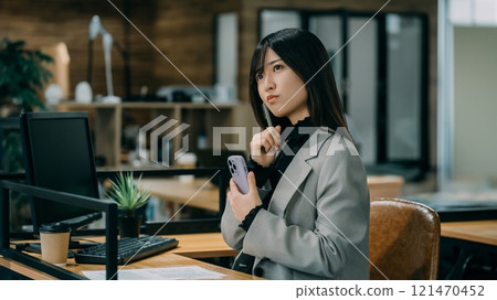 拿著智慧型手機思考的女商人 121470452