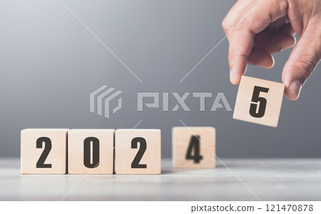 A hand replaces "2024" with "2025" using number blocks, symbolizing the transition into the new year, representing change, progress, and the ongoing passage of time A hand replaces "2024" with "2025" using number blocks, symbolizing the transition into the new year, representing change, progress, and the ongoing passage of time 121470878