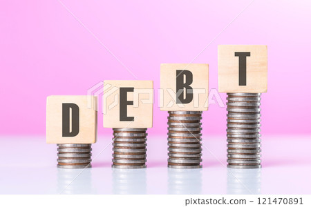 Stack of coins neatly arranged on top of a wooden block labeled "DEBT," symbolizing financial burdens and the weight of monetary obligations, set against a neutral background to emphasize the concept 121470891