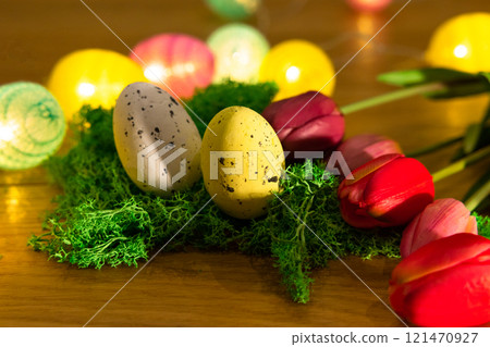 Easter colored eggs on green grass around tulips and wooden board Happy Easter Easter colored eggs on green grass around tulips and wooden board Happy Easter 121470927