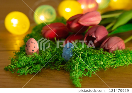 Easter colored eggs on green grass around tulips and wooden board Happy Easter 121470929
