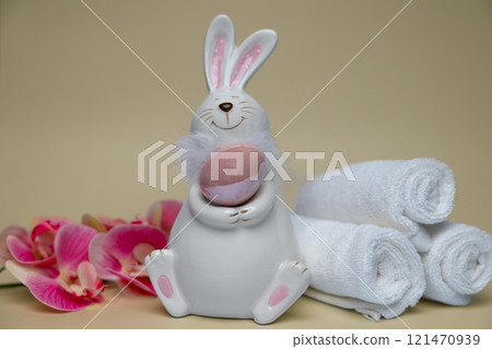 Easter white hare with brown egg on background of orchid flowers white towels 121470939