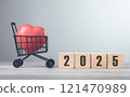 Wooden block with "2025" and a red heart placed in a shopping cart sit on a table, symbolizing future goals and investments in well-being, against a bright grey background 121470989