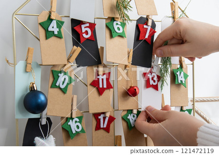 Number on craft paper notes with tasks before Christmas holidays. Female making kraft paper for handmade advent calendar Made with your own hands step by step DIY Number on craft paper notes with tasks before Christmas holidays. Female making kraft paper for handmade advent calendar Made with your own hands step by step DIY 121472119