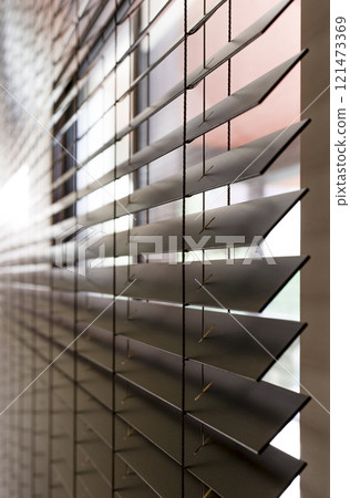 Wooden blinds on a window, close-up, side view. Horizontal blades of 50mm extend into the distance. This is clearly visible ladder and a hole in the blinds for the cord. Wooden blinds on a window, close-up, side view. Horizontal blades of 50mm extend into the distance. This is clearly visible ladder and a hole in the blinds for the cord. 121473369