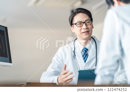 A middle-aged male doctor asking questions while showing an X-ray 121474252