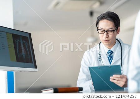 A middle-aged male doctor asking questions while showing an X-ray 121474255