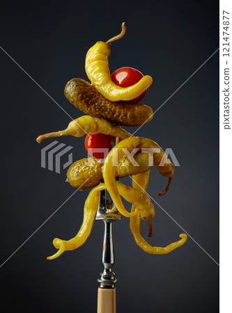 Canned yellow peppers, cucumbers, and tomatoes on a black background. 121474877