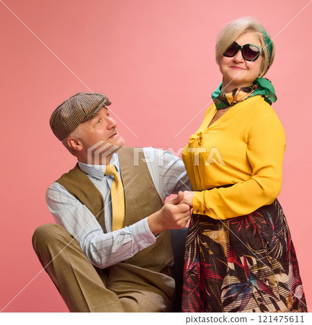 Woman in yellow blouse stands tall with slight smile, man kneeling slightly while holding her hand and looking up appreciatively. Woman in yellow blouse stands tall with slight smile, man kneeling slightly while holding her hand and looking up appreciatively. 121475611