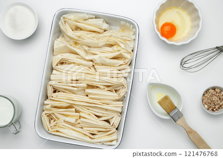 Filo dough in a baking dish near Crinkle Cake butter for buttering 121476768