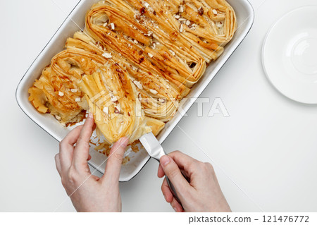 Finished Crinkle Cake made from phyllo dough is cut with a knife Finished Crinkle Cake made from phyllo dough is cut with a knife 121476772