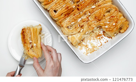Made Crinkle Cake from phyllo dough is cut with a knife 121476773