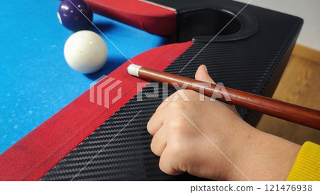 A boy plays billiard or pool in club. Young Kid learns to play snooker. Boy with billiard cue strikes the ball on table. Active Leisure, sport, hobby concept 121476938