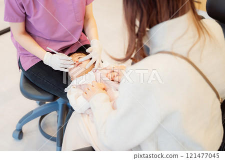 An anxious baby undergoing an infant checkup 121477045