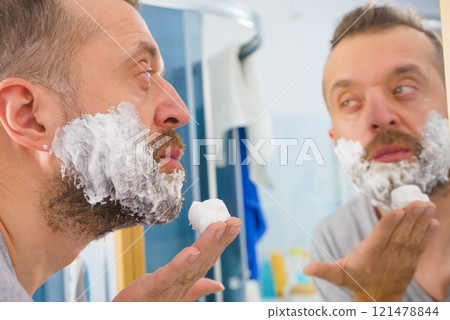 Guy shaving his beard in bathroom Guy shaving his beard in bathroom 121478844