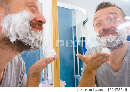 Guy shaving his beard in bathroom Guy shaving his beard in bathroom 121478846