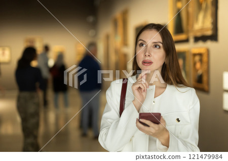 Woman with mobile phone on the background of paintings 121479984