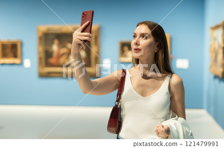 Woman photographs attractive and unusual exhibit, picture and work of applied art. 121479991