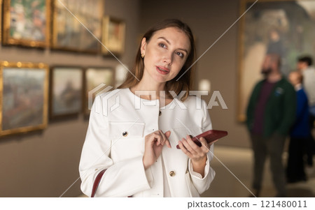 Woman in a Jacket and with a Phone in a Museum of Paintings 121480011