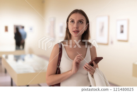 Woman with phone in gallery Woman with phone in gallery 121480025