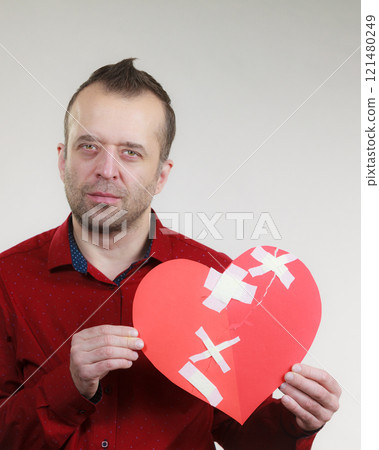 Sad adult man holding broken heart 121480249