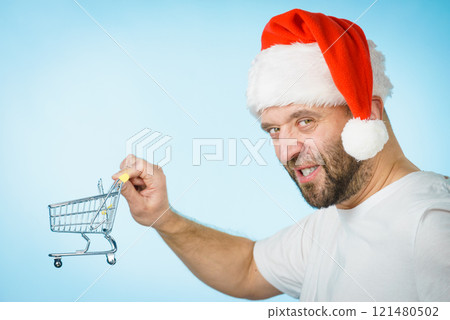 Man in santa hat holds empty shopping cart Man in santa hat holds empty shopping cart 121480502