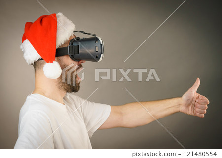 Man in virtual reality goggles and santa hat Man in virtual reality goggles and santa hat 121480554