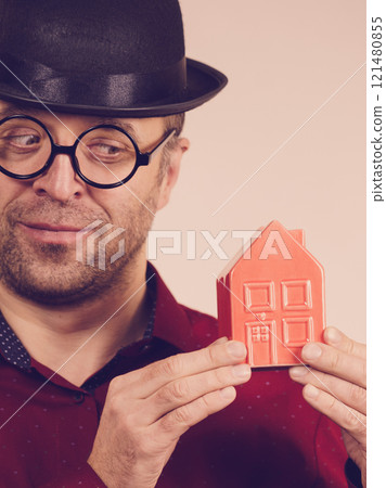 Man wearing funny eyeglasses holding house 121480855