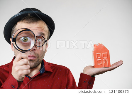 Man magnifying red house Man magnifying red house 121480875