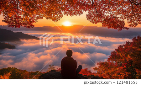 A man enjoying the tranquility of a mountaintop covered in autumn leaves and the rising sun 121481553