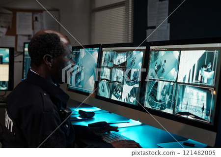 Guard sitting by workplace with monitors 121482005