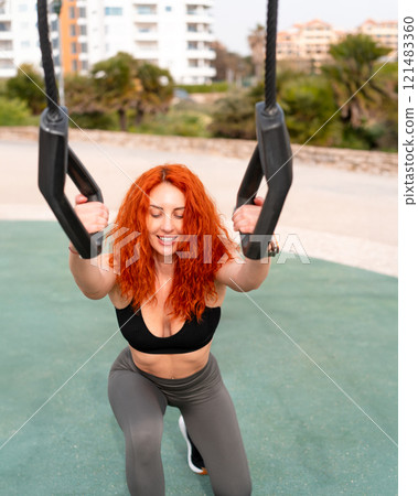 Determined redheaded woman pulling handles on Determined redheaded woman pulling handles on 121483360