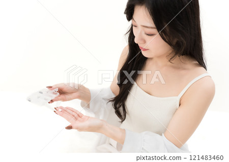 Young woman holding supplement case and pills 121483460