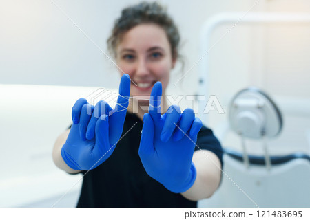 Selective focus on dental floss for dental care in the hands of smiling female dental hygienist 121483695
