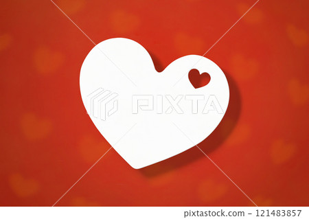 A red heart patterned background with a heart shaped piece of paper cut out of it in the center 121483857