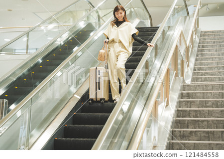 A woman arrives at the airport and descends the escalator A woman arrives at the airport and descends the escalator 121484558