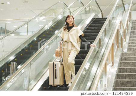 A woman arrives at the airport and descends the escalator 121484559